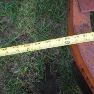 DSCF4523 - Montana Auctions by Kevin Hill Yellow tape measure stretched across green grass beside an orange, rusted metal frame.