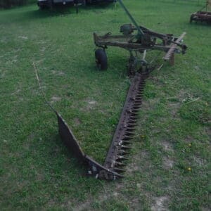 DSCF4530 - Montana Auctions by Kevin Hill Rusty farming cultivator with a long spiked bar extended on grass, attached to a wheeled frame.