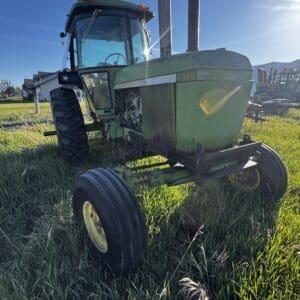 IMG_1296 - Montana Auctions by Kevin Hill Old green tractor in a sunlit field, viewed from the front-right with tall grass surrounding it