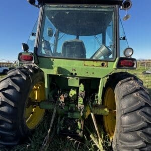 IMG_1300 - Montana Auctions by Kevin Hill Rear view of a green tractor with large yellow wheels parked in tall grass under a clear blue sky.