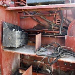 IMG_1325 - Montana Auctions by Kevin Hill Interior of red industrial machine showing tangled wires, a dusty control box, and exposed metal shelves.