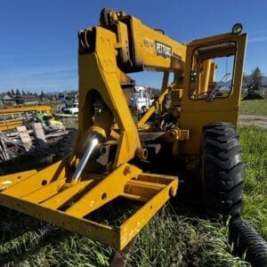 IMG_1347 - Montana Auctions by Kevin Hill Yellow wheeled hydraulic construction machine with a front loader/attachment in a grassy lot, daytime with clear blue sky and background equipment nearby (industrial yard)