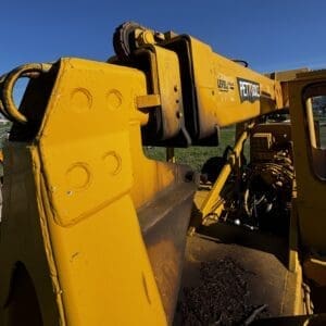 IMG_1348 - Montana Auctions by Kevin Hill Close-up of a yellow construction crane arm with hydraulic joints outdoors under a clear blue sky.