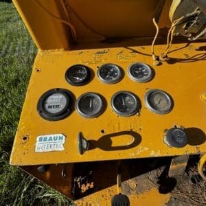 IMG_1350 - Montana Auctions by Kevin Hill Orange industrial control panel with multiple gauges and wiring; Braun Intertec sticker, outdoors on grass field.