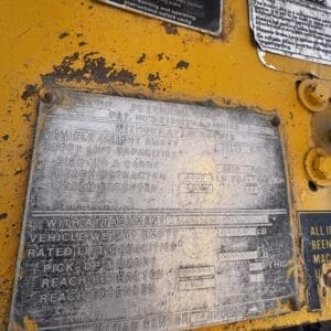 IMG_1351 - Montana Auctions by Kevin Hill Close-up of a weathered metal data plate on yellow heavy machinery, showing lift capacities and reach specifications.