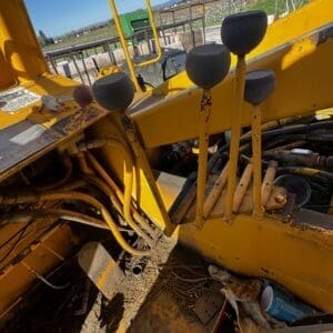 IMG_1352 - Montana Auctions by Kevin Hill Interior of a yellow construction machine showing four black lever handles and a dusty, rust-speckled floor; outdoor yard visible through openings.
