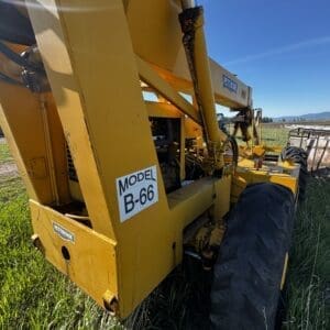IMG_1357 - Montana Auctions by Kevin Hill Yellow Pettibone Model B-66 heavy construction machine parked in a grassy field, blue sky overhead, exposed hydraulics.