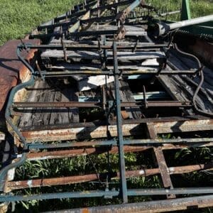 IMG_1360 - Montana Auctions by Kevin Hill Rusty metal farming implement with multiple bars on a weathered wooden trailer in a grassy field.