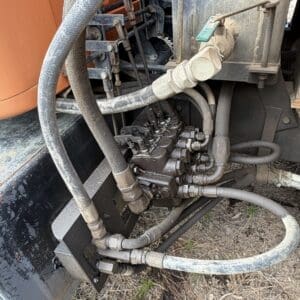 IMG_6531 - Montana Auctions by Kevin Hill Close-up of a dusty hydraulic pump with multiple hoses and metal fittings connected to a heavy machine.