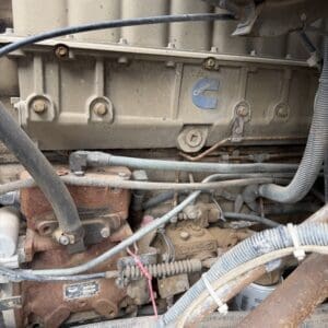 IMG_6539 - Montana Auctions by Kevin Hill Close-up of a dusty Cummins diesel engine in a heavy equipment engine bay, with rusted components and hoses visible.