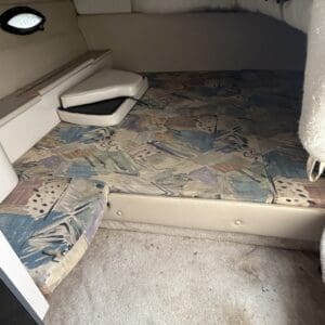 IMG_6560 - Montana Auctions by Kevin Hill Small boat cabin with a raised bed platform, folded cushions, and two porthole windows along the side.