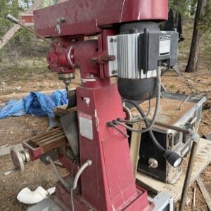 IMG_6570 - Montana Auctions by Kevin Hill Red industrial drill press outdoors on a wooden base, with a black motor and wiring visible