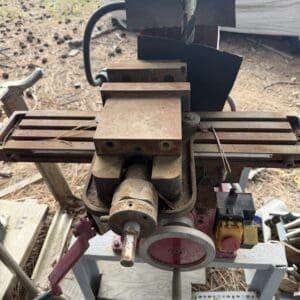 IMG_6571 - Montana Auctions by Kevin Hill Rusty drill press with a two-part vise on a dusty work table outdoors in a yard.