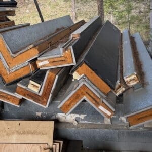 IMG_6574 - Montana Auctions by Kevin Hill Pile of discarded construction panels and framing lumber stacked outdoors, with metal and wood scraps and pine needles on top