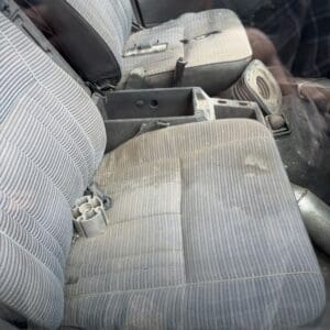 IMG_6591 - Montana Auctions by Kevin Hill Worn car interior with striped front seats, open center console, and a round cup holder on the passenger seat.