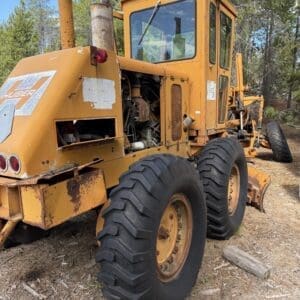 IMG_6631 - Montana Auctions by Kevin Hill Old orange road grader with oversized tires, parked on a dirt lot and showing rusted panels.