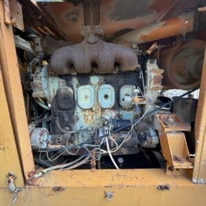 IMG_6636 - Montana Auctions by Kevin Hill Rusty diesel engine exposed inside an orange, weathered industrial machine, with frayed wiring and aged, corroded components visible.
