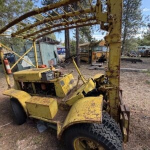IMG_6650 - Montana Auctions by Kevin Hill Weathered yellow utility tractor with a lattice frame canopy in a junkyard, rusted and worn.