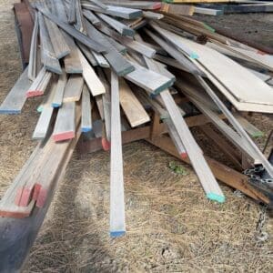 IMG_6655 - Montana Auctions by Kevin Hill Pile of weathered wooden boards stacked on a trailer, ends painted in blue, red, green and other colors.