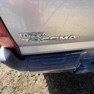 IMG_6677 - Montana Auctions by Kevin Hill Rear view of a gray Toyota Tacoma with chrome emblem on the tailgate.