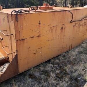 IMG_6690 - Montana Auctions by Kevin Hill Rusted orange industrial storage tank outdoors with rope and metal fittings on a grassy, sunlit site.