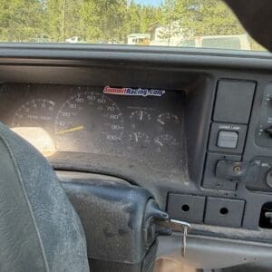 IMG_6698 - Montana Auctions by Kevin Hill Driver's view of a dusty car dashboard; ignition key is in the ignition, with a SummitRacing.com sticker on the instrument cluster visible.