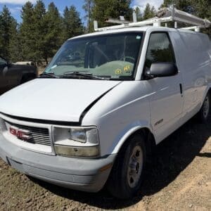 IMG_6703 - Montana Auctions by Kevin Hill White GMC cargo van with a roof ladder rack parked on a dirt lot among pine trees.