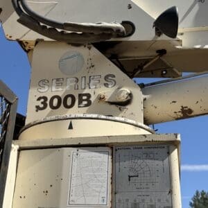IMG_6718 - Montana Auctions by Kevin Hill Industrial crane machinery with a weathered beige body labeled SERIES 300B, showing control dials, cables, and instruction panels on the surface against a blue sky.