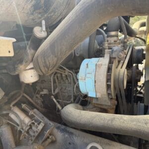 IMG_6724 - Montana Auctions by Kevin Hill Dirt-streaked engine bay with a blue alternator and belt drive visible among hoses and components.