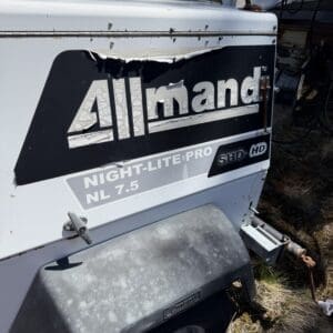 IMG_6729 - Montana Auctions by Kevin Hill Rear view of a damaged Allmand Night-Lite Pro NL 7.5 light tower on a trailer, with a torn logo panel and rusted housing.