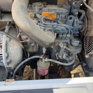 IMG_6730 - Montana Auctions by Kevin Hill Dusty diesel engine with a large curved intake hose, orange warning labels, and a red oil/fuel filter visible.