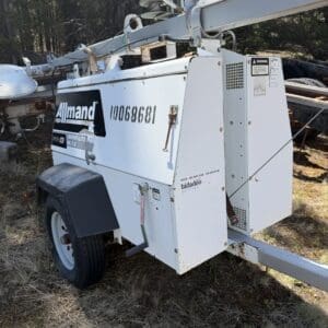 IMG_6732 - Montana Auctions by Kevin Hill White Allmand portable light tower on a trailer parked on dry grass with trees in the background, used for outdoor lighting at worksites.
