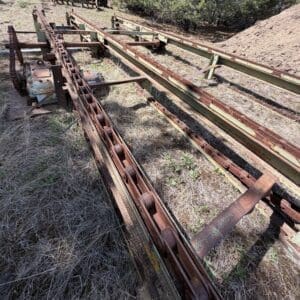 IMG_6751 - Montana Auctions by Kevin Hill Abandoned, rusted conveyor-like tracks and framework resting on dry grass in a rural field.