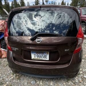IMG_6773 - Montana Auctions by Kevin Hill Rear view of a brown Nissan Versa Note SV with Montana license plate 7-96658E, reflecting clouds in the rear window.