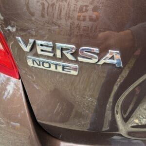 IMG_6774 - Montana Auctions by Kevin Hill Brown Nissan Versa Note rear with chrome emblems, showing 'VERSA' and 'NOTE' badges on trunk