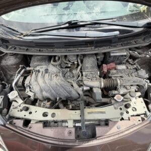 IMG_6781 - Montana Auctions by Kevin Hill Front view of a dusty car engine bay with battery, radiator, and intake manifold visible under an open hood.