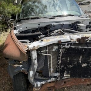 IMG_6799 - Montana Auctions by Kevin Hill Front view of a severely damaged pickup truck with exposed radiator, rusted frame, and missing bumper.