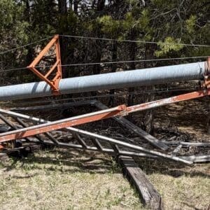IMG_6817 - Montana Auctions by Kevin Hill Damaged agricultural irrigation boom lying on the ground with bent metal arms and a yellow-wheel cart in a grassy yard.