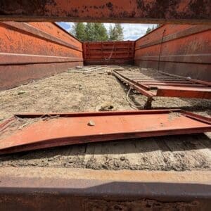 IMG_6824 - Montana Auctions by Kevin Hill Rusty red trailer bed with scattered boards, rope, and dirt inside, seen from near the floor looking toward the back.