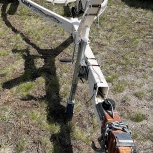 IMG_6838 - Montana Auctions by Kevin Hill Front view of a white boat trailer frame on grassy ground, showing the hitch with safety chains and winch components ready to tow.