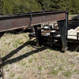 IMG_6846 - Montana Auctions by Kevin Hill Rusty flatbed trailer frame on a dry grassy field, chains and hitch in the foreground.