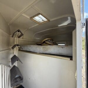 IMG_6852 - Montana Auctions by Kevin Hill Interior of a small camper where a bed platform holds a mattress and loose gear; foam stair steps lean against the wall.