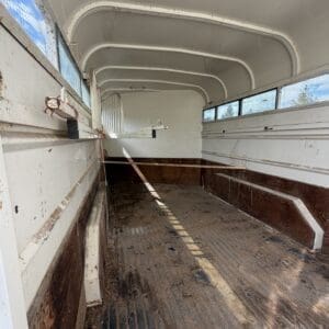 IMG_6855 - Montana Auctions by Kevin Hill Empty horse trailer interior with white curved ceiling, side stalls, and a dirt floor running lengthwise.