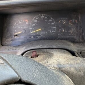 IMG_6863 - Montana Auctions by Kevin Hill Driver's view of a dusty dashboard with speedometer, tachometer, and fuel gauges visible through the steering wheel.