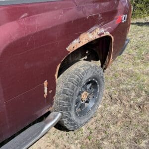 IMG_6875 - Montana Auctions by Kevin Hill Maroon pickup truck with significant rust around the rear wheel well and a large off-road tire exposed.