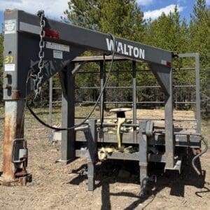 IMG_6884 - Montana Auctions by Kevin Hill Industrial metal framework with rust, chains, and yellow straps outdoors; trees in background and a large beam labeled Walton.