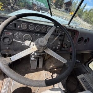 IMG_6903 - Montana Auctions by Kevin Hill Interior of an old dusty pickup truck: large three-spoke steering wheel and weathered dashboard with gauges and switches