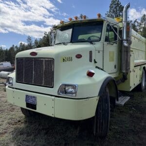 IMG_6908 - Montana Auctions by Kevin Hill Light-green Peterbilt semi-truck parked on grass under a blue sky with clouds