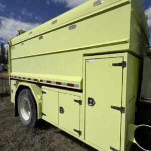 IMG_6910 - Montana Auctions by Kevin Hill Side view of a lime-green utility work truck with multiple lockable storage compartments against a blue sky and grassy ground.