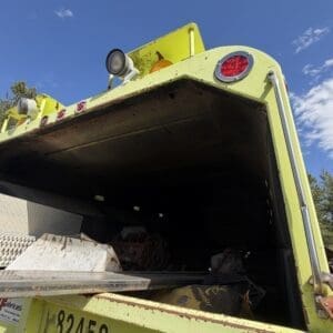 IMG_6912 - Montana Auctions by Kevin Hill Rear view of a lime-green utility truck with an open, rust-speckled bed and red taillights against a clear blue sky.
